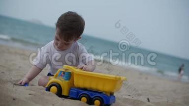 两岁漂亮的婴儿学步<strong>男</strong>孩骑着玩具货车在<strong>夏季</strong>海滩特写。 慢动作
