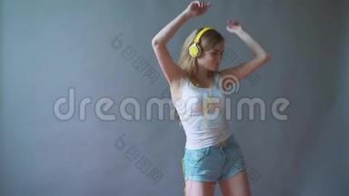 灰色背景的年轻美女，听着耳机里的音乐，跳舞