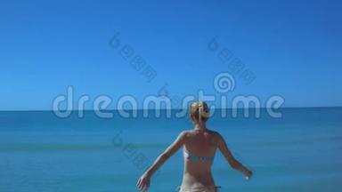 美丽苗条的女孩沿着海边的海滩奔跑，奔跑着年轻的女人