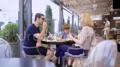 一家人和儿子一起在餐馆的露台上吃饭。