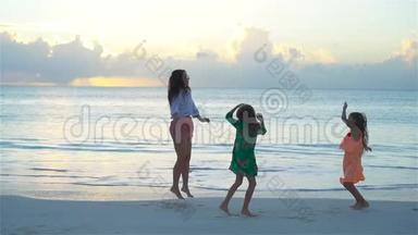 妈妈和孩子们享受海滩暑假热带假期。 一家人在白色海滩跳舞。 流动人口
