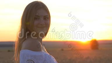 太阳落山时麦田里一个年轻漂亮女孩的脸。 我脸上洋溢着快乐的表情和微笑