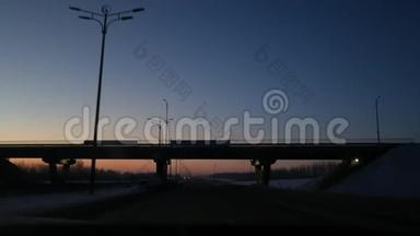 从车窗上可以看到汽车在昏暗的冬季道路上行驶，在桥下行驶