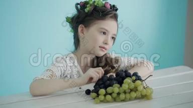 小女孩拿着葡萄摆姿势给坐在桌边的摄影师拍照