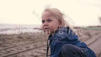 可爱的小女孩坐在岸边<strong>玩沙子</strong>。 她手里拿着<strong>沙子</strong>