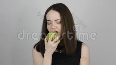 迷人的年轻女人吃着绿色的苹果，微笑着