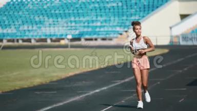 一个穿着运动服的强壮女孩在<strong>体育场</strong>奔跑的肖像。 美丽的女孩在<strong>体育场</strong>奔跑，倾听