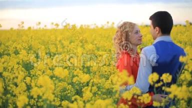 这对可爱的情侣用黄色盛开的花朵在田野上轻轻拥抱和亲吻的肖像。