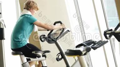 一个年轻人在健身房骑健身自行车的<strong>加速</strong>镜头
