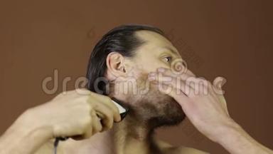 男人用电动剃须刀剪脸，大胡子