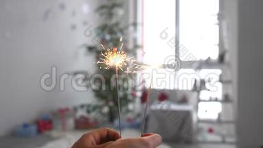 女孩的手`圣诞树前燃烧的火花。 慢动作。 3840x2160，4k