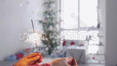 女孩的手在圣诞树前拿着燃烧的火花。慢动作。3840x2160