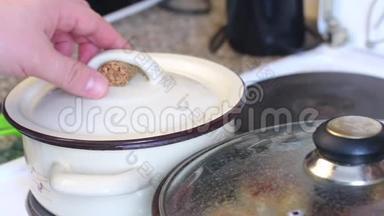 一个人检查意大利面的准备情况。把锅盖从锅里拿出来，勺子搅动里面的东西。