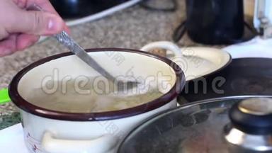 一个人检查意大利面的准备情况。把锅盖从锅里拿出来，勺子搅动里面的东西。