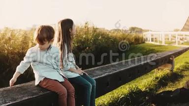 两个<strong>白人小孩</strong>坐在农村的围栏上。 男孩和女孩在阳光明媚的麦田附近环顾四周。 向左转。 4K.