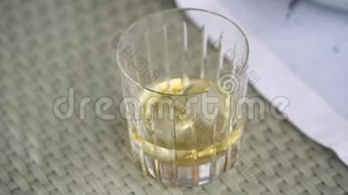 服务员把冰块放进装有威士忌的玻璃杯里，桌子上放一杯威士忌，一杯威士忌放冰块，一杯