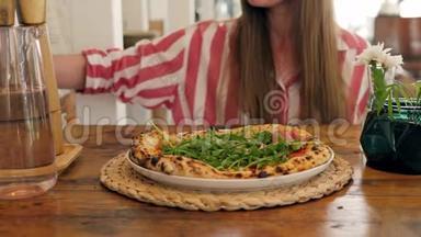 披萨店的厨师准备一个披萨，并用意大利火腿装饰它。 绿色草本植物接近