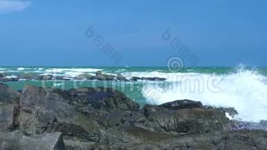 波涛汹涌的大海和海浪溅落在岩石海滩上的蓝天景观。 海浪在海洋中的石滩上肆虐