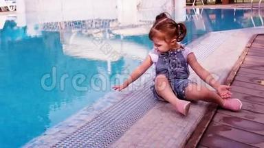 蓝色游泳池旁的小女孩。 一个小孩子在游泳池旁边玩。 一个漂亮的小女孩正坐在一个
