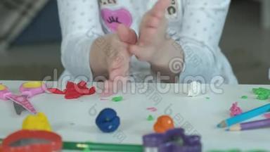 一个小女孩玩橡皮泥，用手把它卷起来，桌面上有数字和彩色铅笔