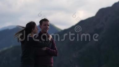 两个人在山的背景下散步。 蜜月。 亲吻山脉的背景。 风的发展