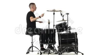 职业音乐家用棍子在鼓上演奏音乐。 白色背景。 侧视图