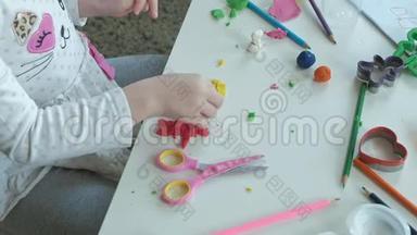 快乐的小女孩玩橡皮泥，雕刻一个图形，<strong>桌面上</strong>是图形和彩色铅笔，