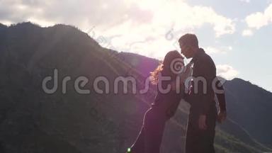 两个人在山的背景下散步。 蜜月。 在群山的背景上亲吻。 风力发展