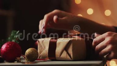 在圣诞灯光的背景下，女人`手把<strong>丝带绑</strong>在牛皮纸上。 背景