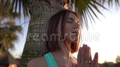 一个年轻<strong>漂亮</strong>的女孩在棕榈<strong>树上</strong>做瑜伽。 慢速运动4k