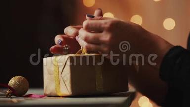 在圣诞灯光的背景下，女人`手把<strong>丝带绑</strong>在牛皮纸上。 背景
