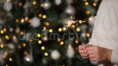 一名女子手中握着燃烧的孟加拉灯，`圣诞树后的近距离射击