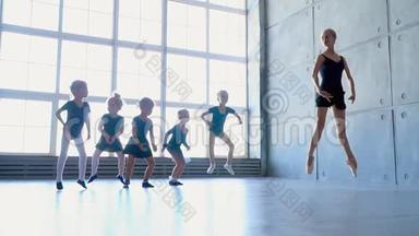 小女孩试图重复芭蕾职业的动作。 芭蕾舞学校里的小芭蕾舞演员舞蹈，全景