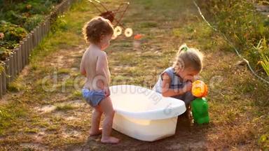 快乐开朗的孩子在暑假玩水.. 可爱可爱的微笑的孩子们在花园里喷洒