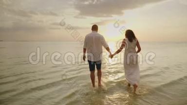 浪漫的情侣在日落时在海边散步。 蜜月和海边度假的概念
