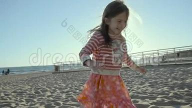 笑着的小女孩一边跑在海边，一边跌跌撞撞地钻进沙里