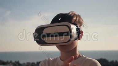 日落时快乐的男孩，戴着虚拟现实眼镜，玩电子游戏，快乐的微笑，看着VR眼镜和虚拟现实眼镜
