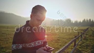 帅哥在日落时使用智能手机户外，在大自然中使用LenseFlare