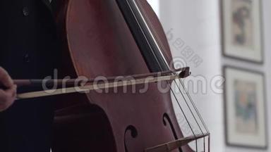 当大提琴手拉着她的弓时，大提琴琴弦的特写