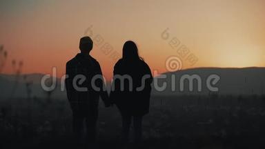 恋爱中的年轻夫妇在山上欣赏日落的剪影。 假期，旅行，浪漫，<strong>求婚</strong>