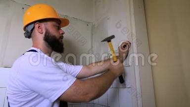 建筑工人和杂工<strong>用</strong>黄色锤子敲击，并在施工现场的厨房门的木墙上钉钉子