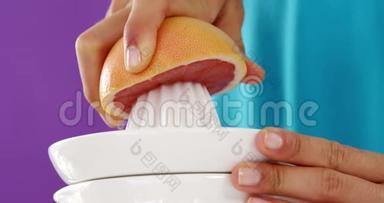 女人用榨汁机在紫罗兰色背景下配制血橙汁