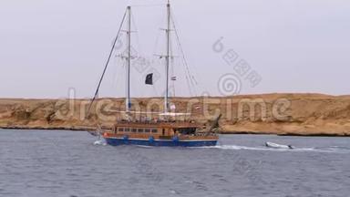美丽的旅游游艇在岩石的背景下在波涛汹涌的大海中航行。 埃及