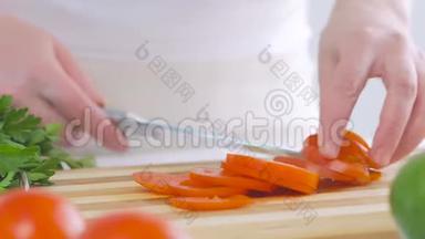 一个女人在厨房里切一个西红柿，准备一份美味的新鲜蔬菜沙拉作<strong>为</strong>午餐