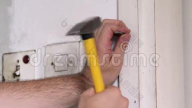 建筑工人和杂工用黄色锤子敲击，并在施工现场的厨房门的木墙上钉钉子