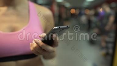 女人在手机上<strong>翻页</strong>，在健身房锻炼后休息