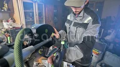 一个留着灰色工作服胡须的年轻人，一个木匠在家里用一台圆形切割机工作