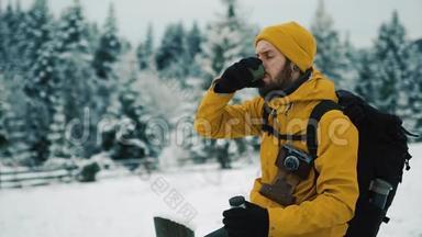 冬天美丽的山。 有胡子的人穿着黄色的冬装，在外面喝热茶或咖啡