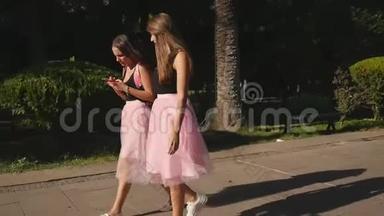 两位穿着薄纱裙和运动鞋的年轻美女在户外散步