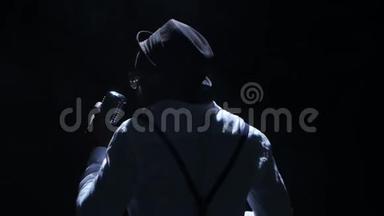 歌手的视线从后面的烟雾和白光，拿着他的麦克风和手势的手唱歌。 黑色
